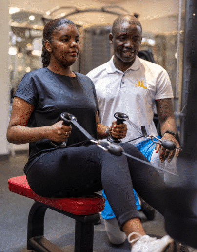 Une étudiante pratiquant la musculation sous la direction d'un entraîneur qualifié dans une salle de fitness.