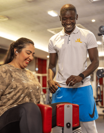 Un coach sportif et une étudiante souriant ensemble lors d'une séance d'entraînement, illustrant la motivation et le plaisir du sport.